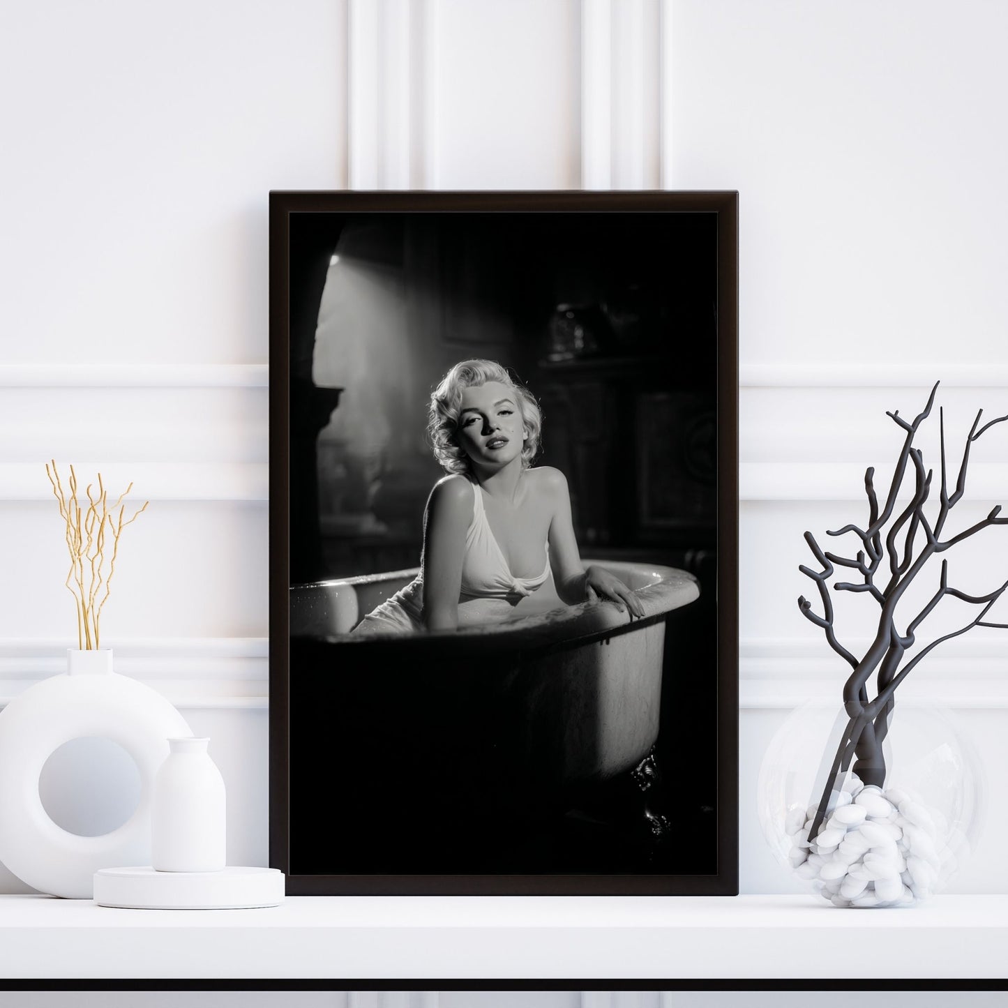 Framed black and white portrait of a person in a bathtub on a white wall.