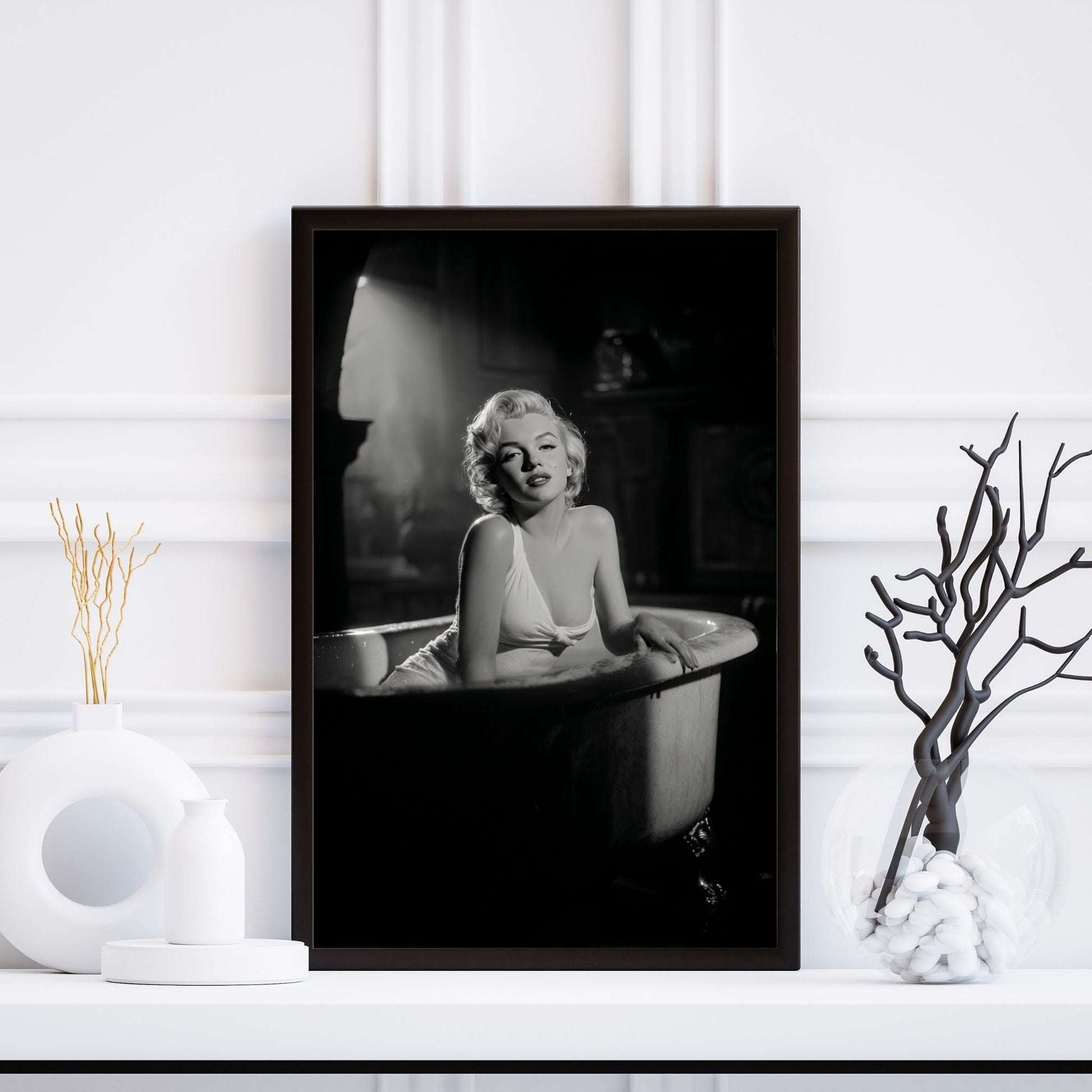 Framed black and white portrait of a person in a bathtub on a white wall.