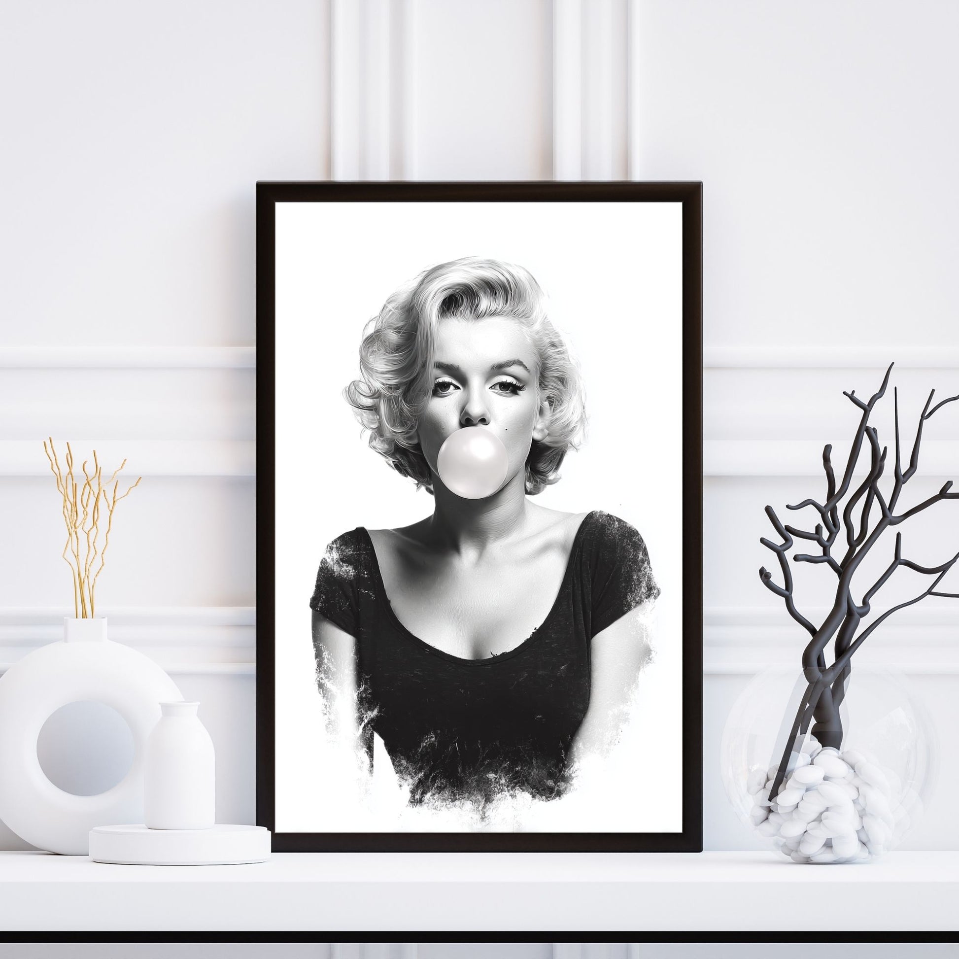 Framed black and white portrait of a woman blowing a bubble, placed on a white surface with decorative elements.
