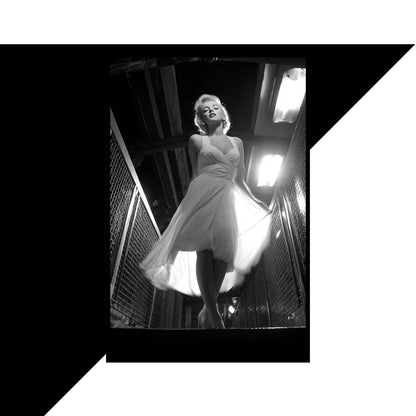 Black and white photo of a woman in a dress standing in an urban setting.