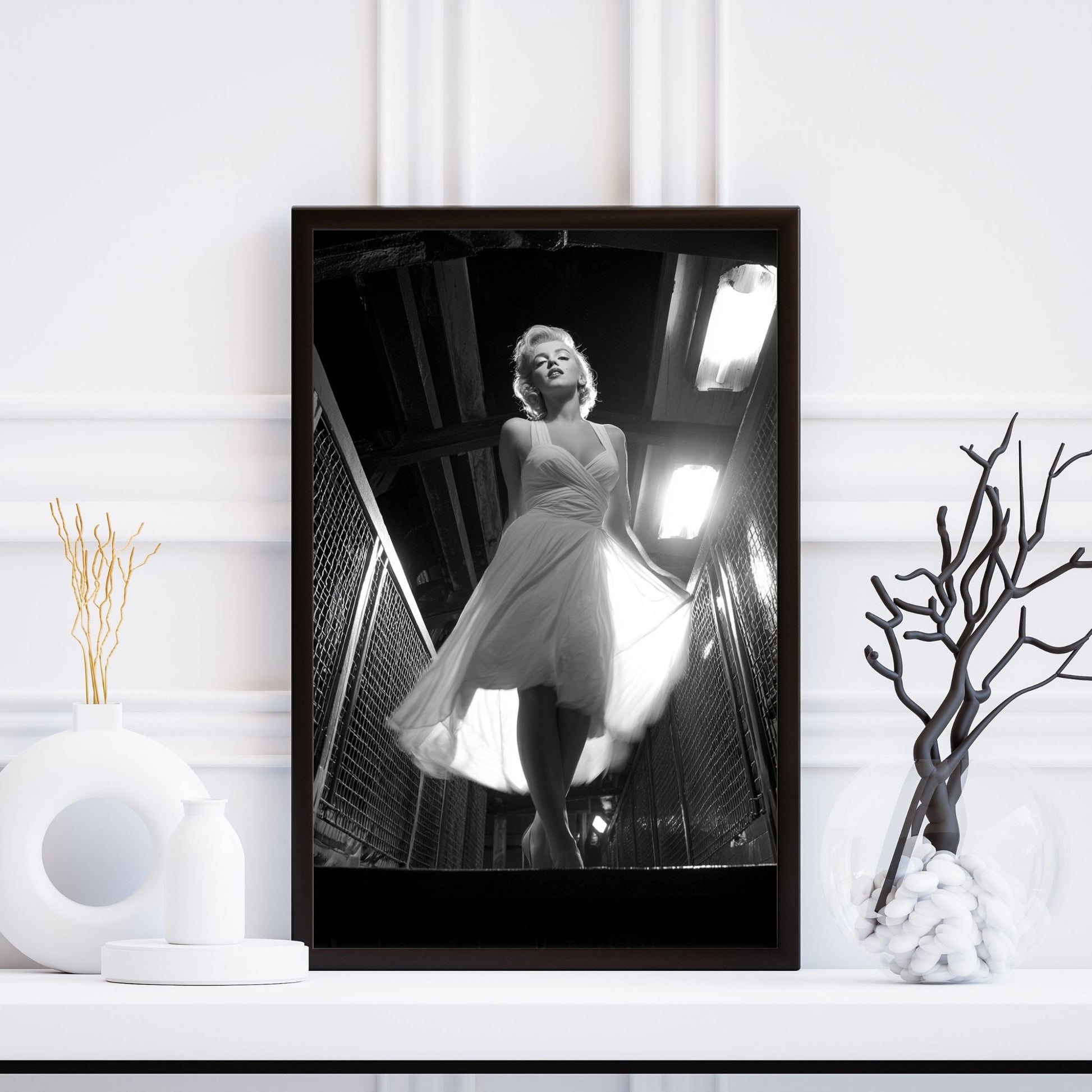 Framed black and white photo of a woman in a dress on a white wall.